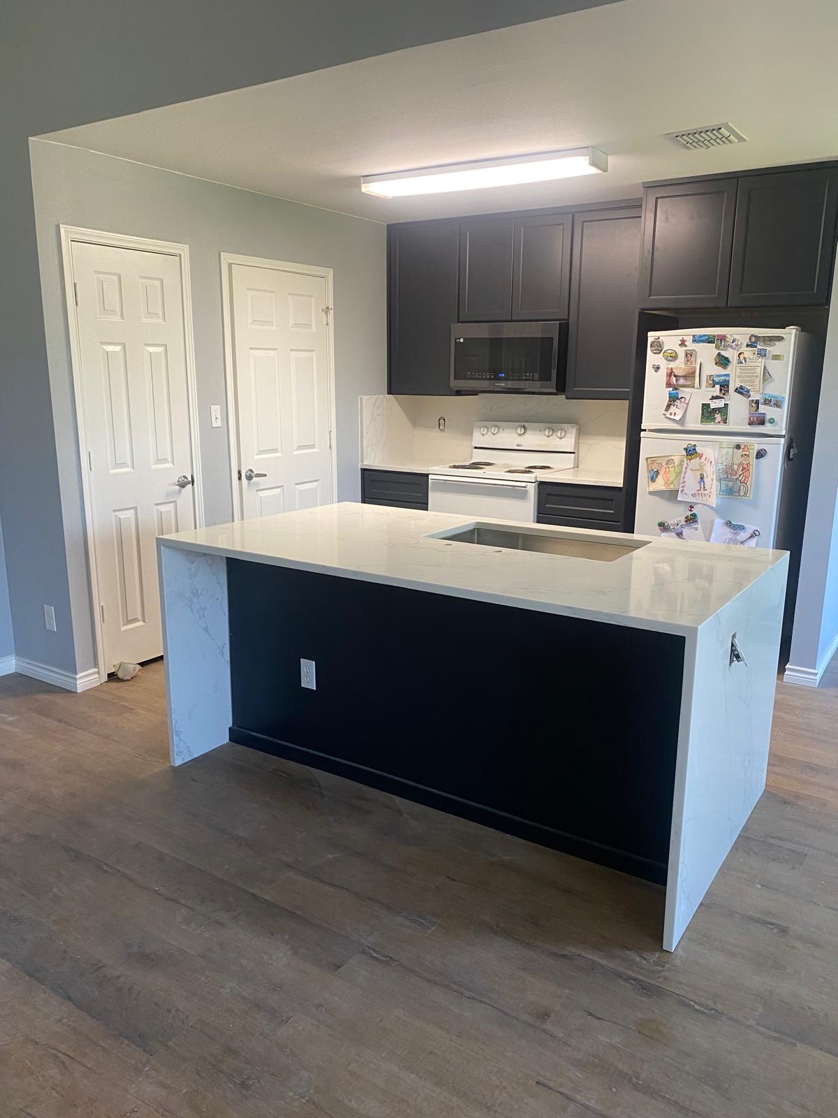 Waterfall quartz island installed by Azteca Granite, with matching countertops and backsplash